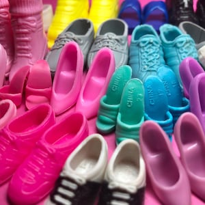 May include: A collection of colorful miniature shoes, including pink boots, high heels, sneakers, and sandals. The shoes are in various shades of pink, blue, green, yellow, and white. Some shoes have the word "CHINA" printed on them.