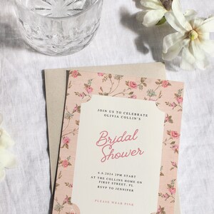 May include: A pink floral bridal shower invitation with the text "JOIN US TO CELEBRATE OLIVIA COLLIN'S Bridal Shower 6.6.2024 2PM START AT THE COLLINS HOME ON FIRST STREET, FL RSVP TO JENNIFER PLEASE WEAR PINK"