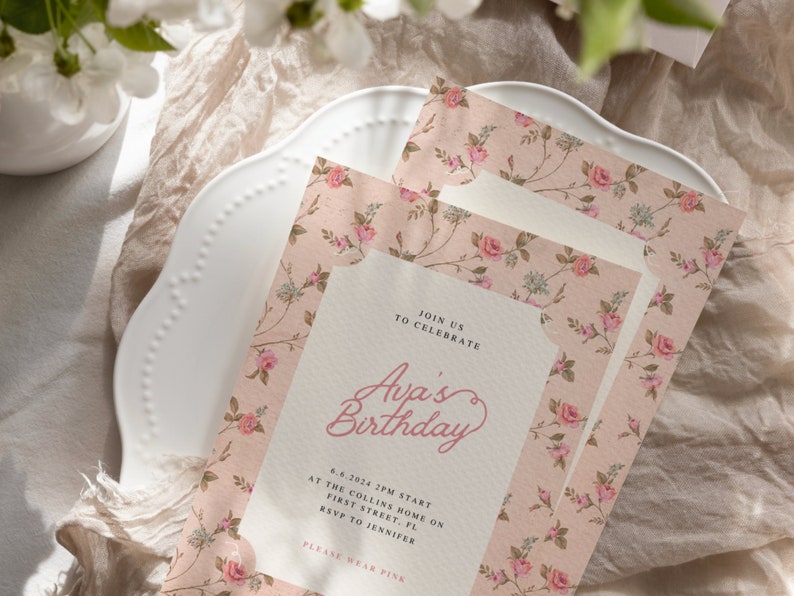 May include: A pink floral patterned invitation card with the text "Join us to celebrate Ava's Birthday" and details for the event. The invitation is on a white plate with a floral pattern.