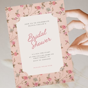 May include: A pink floral patterned invitation for a bridal shower. The invitation reads "Join us to celebrate Olivia Collin's Bridal Shower" and includes the date, time, location, and RSVP information. It also says "Please wear pink".