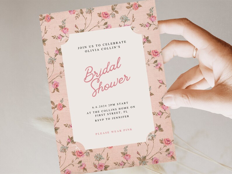 May include: A pink floral patterned invitation for a bridal shower. The invitation reads "Join us to celebrate Olivia Collin's Bridal Shower" and includes the date, time, location, and RSVP information. It also says "Please wear pink".