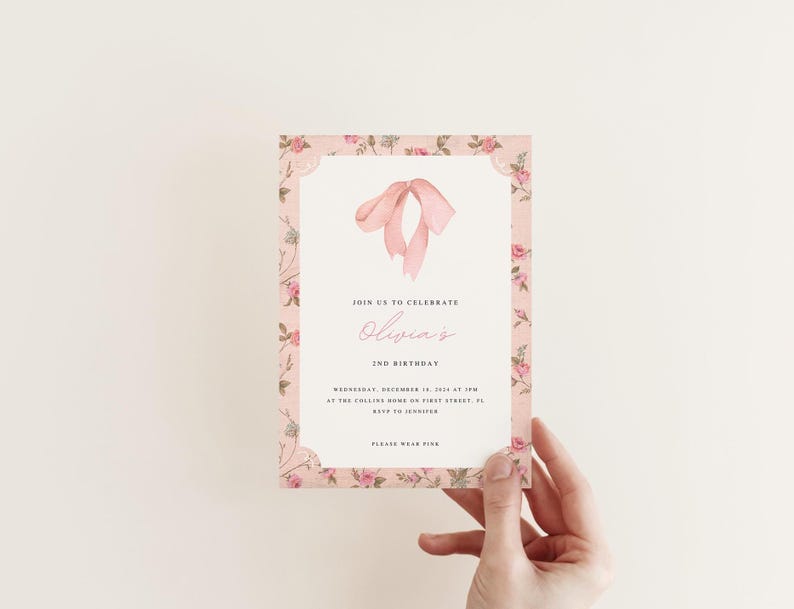 Pu&ograve; includere: Invito floreale rosa con bordo bianco e un fiocco di nastro rosa. L'invito recita "Unisciti a noi per celebrare il 2&deg; compleanno di Olivia".