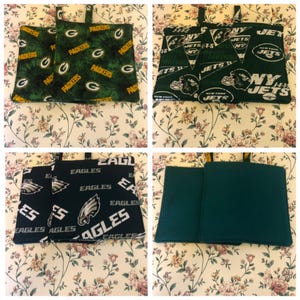 Puede incluir: Conjunto de cuatro agarraderas de olla de tela verde y negra. Dos agarraderas tienen un fondo verde con las palabras "Packers" y una "G" verde repetidas en todo el fondo. Una agarradera tiene un fondo verde con las palabras "New York Jets" repetidas en todo el fondo. Una agarradera tiene un fondo negro con las palabras "Eagles" repetidas en todo el fondo.