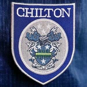May include: A blue and white embroidered patch with the word "CHILTON" in white lettering. The patch features a crest with a green and white design.