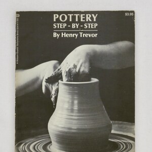 May include: Black and white book cover titled "POTTERY STEP-BY-STEP" by Henry Trevor. The image shows hands shaping a clay pot on a pottery wheel. The book's price is $3.95.