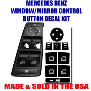 May include: A black decal kit for Mercedes Benz window and mirror controls. The kit includes decals for the window controls, mirror controls, and the control knob. The decals are black with white outlines. The text "MADE & SOLD IN THE USA" is printed below the decals.