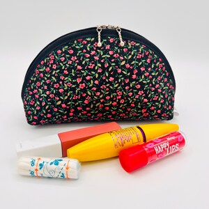 Piccola borsa nera per il trucco floreale con fiori sparsi
