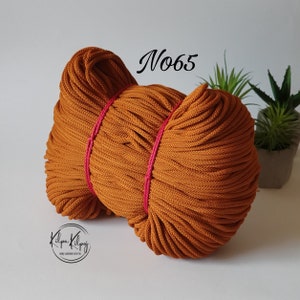 May include: A close-up of a large spool of brown cotton cord. The cord is tightly wound and has a rough texture. The spool is labeled "N065".
