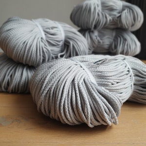 May include: A close-up of a pile of gray cotton rope. The rope is tightly wound and has a soft, textured surface.