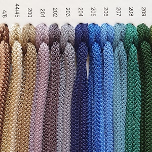 May include: A colour chart of 15 different shades of cord, ranging from dark grey to light green. The cord is woven with a textured pattern. The numbers 12/15, 4/8, 44/45, 200, 201, 202, 203, 204, 205, 206, 207, 208, 209, 210, and 211 are printed above each colour.