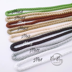 May include: A close-up of ten different colours of braided cord, labelled with numbers. The cords are arranged vertically, with the green cord at the top and the white cord at the bottom. The cords are all the same thickness and have a similar braided pattern.