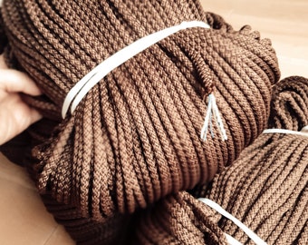 May include: Two spools of brown cord wrapped with white tape. The cord is tightly wound and has a rough texture.