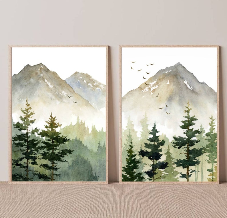 Puede incluir: Dos acuarelas de un paisaje de monta&ntilde;a con un bosque en primer plano. Las pinturas est&aacute;n enmarcadas en madera y est&aacute;n colgadas en una pared de color beige claro.