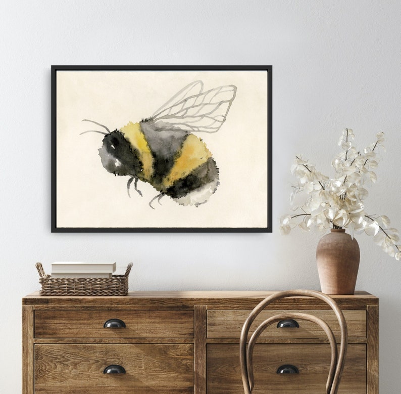 May include: Watercolor painting of a bumblebee with black and yellow stripes and translucent wings on a cream background.