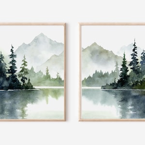 May include: A set of two watercolor paintings depicting a misty mountain lake scene with evergreen trees and a reflection of the mountains in the water.