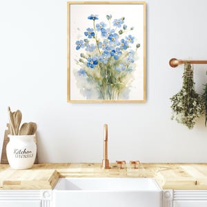 May include: A watercolour painting of a bunch of blue forget-me-not flowers in a wooden frame. The painting is hanging on a white wall above a kitchen sink.
