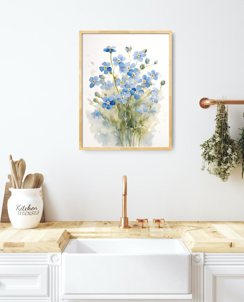 May include: A watercolour painting of a bunch of blue forget-me-not flowers in a wooden frame. The painting is hanging on a white wall above a kitchen sink.