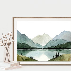 May include: Watercolor painting of a mountain range with a lake in the foreground. The mountains are painted in shades of green and blue, and the lake is a light blue. The painting is framed in a wooden frame.