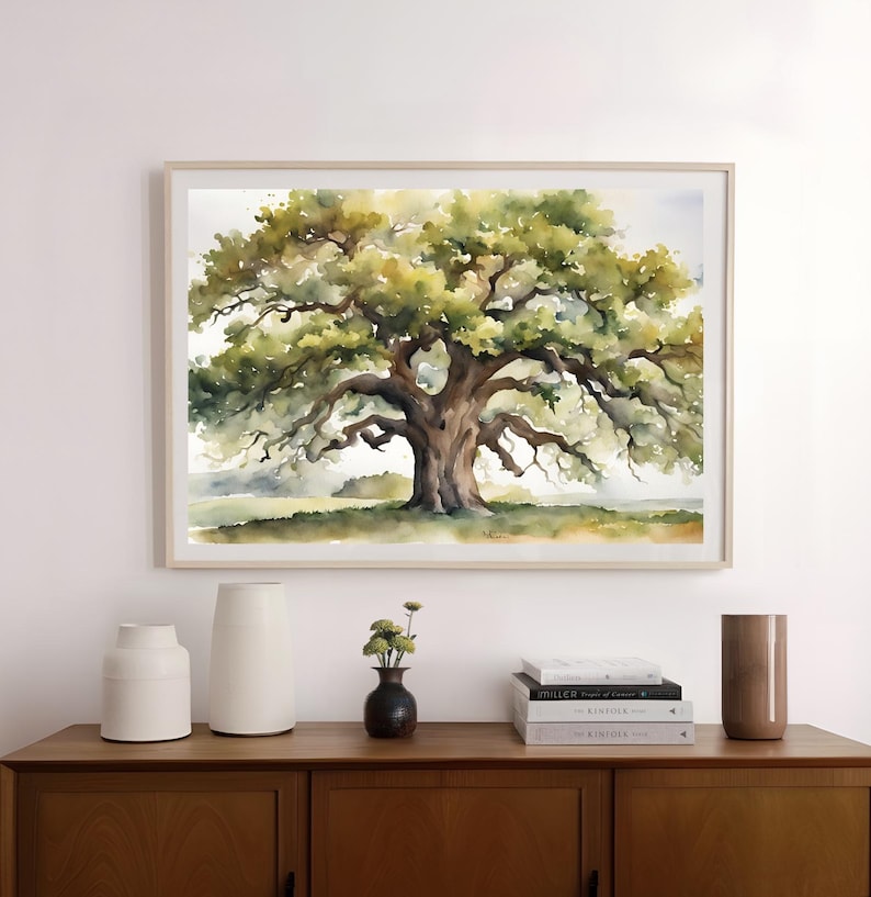 May include: Watercolor painting of a large oak tree with sprawling branches and lush green foliage. The artwork is framed in a light wood frame and hangs above a wooden cabinet. Decorative vases and books are on the cabinet.