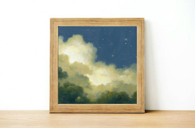 May include: A framed painting of a night sky with clouds and stars. The clouds are a soft yellow and white, and the sky is a deep blue. The stars are small and white.