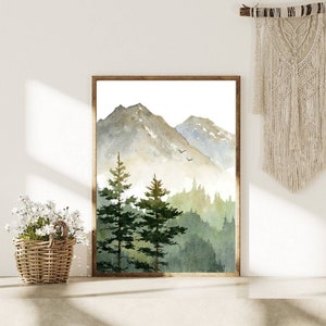 May include: A watercolor painting of a mountain range with a forest in the foreground. The mountains are painted in shades of gray and blue, while the forest is painted in shades of green. The painting is framed in a brown frame.