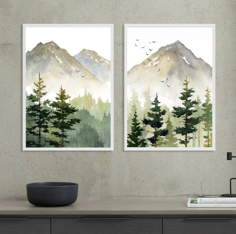 Puede incluir: Dos pinturas de acuarela enmarcadas de una cordillera con un bosque en primer plano. Las pinturas est&aacute;n en marcos blancos y est&aacute;n colgadas en una pared gris.