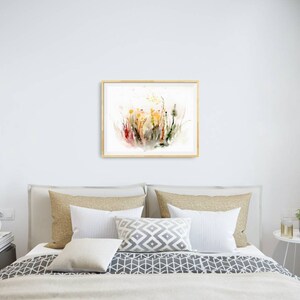 K&ouml;nnte beinhalten: Ein gerahmtes Aquarellbild mit einem farbenfrohen abstrakten Blumendesign mit Spritzern in Rot, Gelb und Gr&uuml;n auf wei&szlig;em Hintergrund.