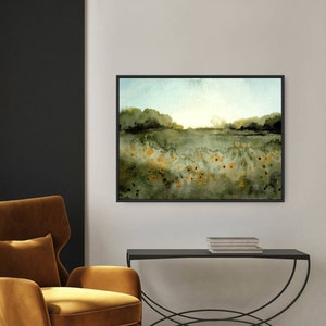 May include: A watercolor painting of a field of yellow wildflowers in a green landscape. The painting has a soft, dreamy feel and is framed in a black frame.