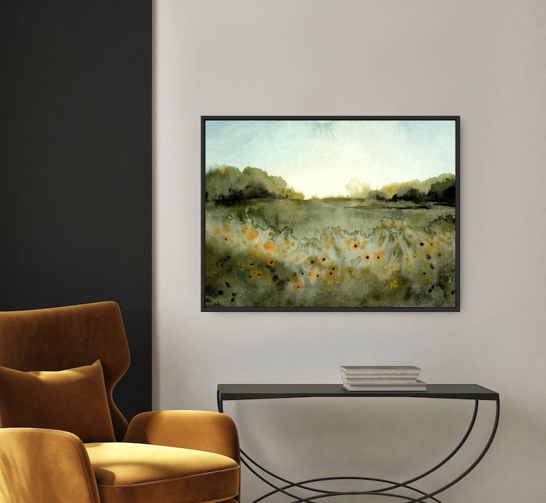 May include: A watercolor painting of a field of yellow wildflowers in a green landscape. The painting has a soft, dreamy feel and is framed in a black frame.
