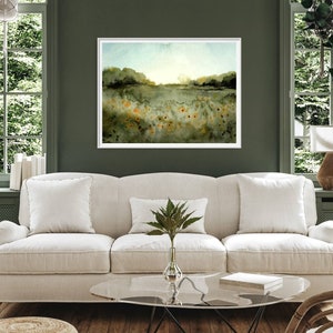 May include: A watercolor painting of a field of wildflowers with a green background and a blue sky. The painting is framed in a white frame and is hanging on a green wall.