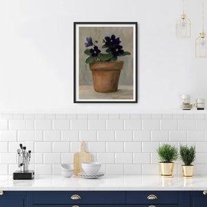 May include: A painting of a potted purple African violet plant with yellow centers. The plant is in a terracotta pot and is sitting on a light gray surface.