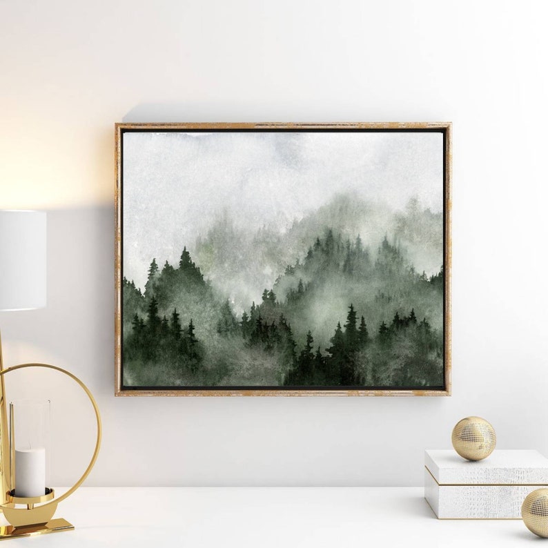 May include: A watercolour painting of a misty forest scene with green trees and a light grey sky. The painting is framed in a light wood frame.