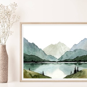 May include: Watercolor painting of a mountain range with a lake in the foreground. The mountains are painted in shades of blue and green, and the lake is a light blue. The painting is framed in a light wood frame.