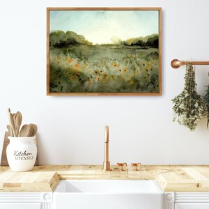 May include: A framed watercolor painting of a landscape with a field of yellow flowers in the foreground and a hazy blue sky in the background.