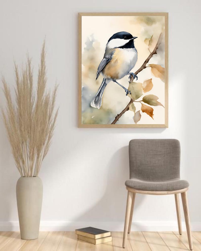 May include: A watercolor painting of a black-capped chickadee perched on a branch with brown leaves. The bird is facing the right side of the image and has a light brown body with a black cap and bib. The background is a soft watercolor wash of light brown and blue.