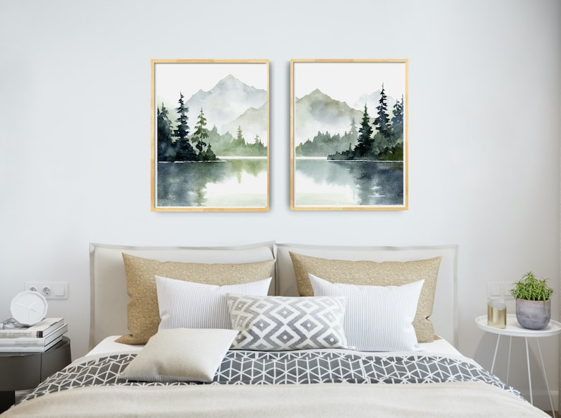 May include: Two framed watercolor paintings of a misty mountain lake scene with green trees and a reflection of the mountains in the water.