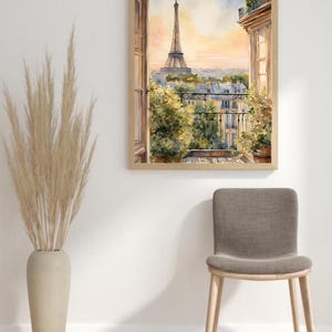 K&ouml;nnte beinhalten: Ein Aquarellbild eines Pariser Balkons mit Blick auf den Eiffelturm. Das Bild ist in einem hellen Holzrahmen gerahmt und h&auml;ngt an einer wei&szlig;en Wand.