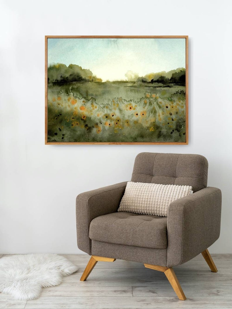 May include: A framed watercolor painting of a field with green trees and yellow flowers in the foreground. The sky is a light blue with a hint of orange in the distance.