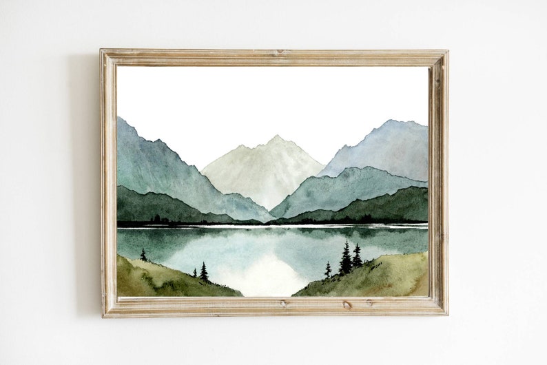 May include: Watercolor painting of a mountain range with a lake in the foreground. The mountains are painted in shades of green and blue, and the lake is a deep blue. The painting is framed in a light wood frame.