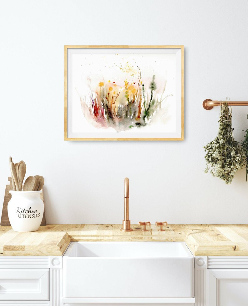 K&ouml;nnte beinhalten: Ein Aquarellbild eines Feldes mit Wildblumen in Gelb-, Orange-, Rot- und Gr&uuml;nt&ouml;nen. Das Bild ist in einem hellen Holzrahmen gerahmt und h&auml;ngt an einer wei&szlig;en Wand.
