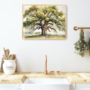 May include: Watercolor painting of a large oak tree with a wide canopy and a thick trunk. The artwork is framed in a light wood frame. The painting has green, brown, and yellow hues. The artwork is displayed above a white sink in a kitchen.