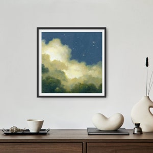 May include: A framed painting of a night sky with clouds and stars. The clouds are a light yellow and the sky is a dark blue. The stars are white.