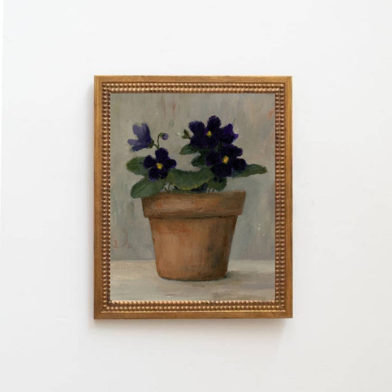 May include: A painting of a potted violet plant with purple flowers and yellow centers. The plant is in a terracotta pot and is set against a light gray background. The painting is framed in a gold frame.