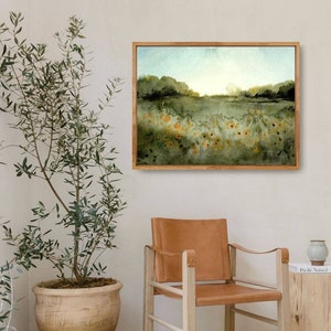 May include: A framed watercolor painting of a field of yellow wildflowers with a green background and a blue sky. The painting is hanging on a white wall above a brown leather chair.