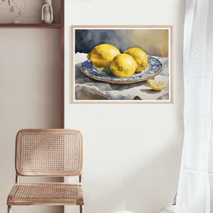 May include: Watercolor painting of three yellow lemons on a blue and white patterned plate. The lemons are arranged in a still life composition on a white tablecloth.