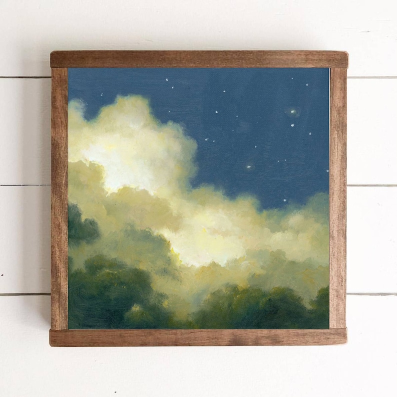 May include: A framed painting of a night sky with clouds and stars. The clouds are a soft yellow and white, and the sky is a deep blue. The stars are small and white.