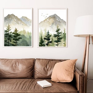 Puede incluir: Dos acuarelas de una cordillera monta&ntilde;osa con un bosque en primer plano. Las pinturas est&aacute;n enmarcadas en blanco y est&aacute;n colgadas en una pared blanca. Las pinturas est&aacute;n en un sal&oacute;n con un sof&aacute; de cuero marr&oacute;n y un coj&iacute;n marr&oacute;n.