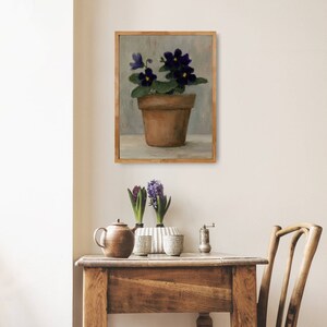 May include: A painting of a potted plant with purple flowers. The plant is in a terracotta pot and is sitting on a table. The background is a light gray color.