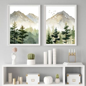 Puede incluir: Dos acuarelas de una cordillera monta&ntilde;osa con un bosque en primer plano. Las pinturas est&aacute;n enmarcadas en blanco y colgadas en una pared gris sobre una estanter&iacute;a blanca con art&iacute;culos decorativos.