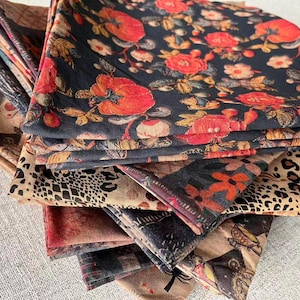 Peut inclure: Une pile de carrés de tissu pliés avec divers motifs. La couche supérieure présente un fond sombre avec de grands motifs floraux rouges et oranges. D'autres motifs incluent l'imprimé léopard et des motifs botaniques et abstraits.